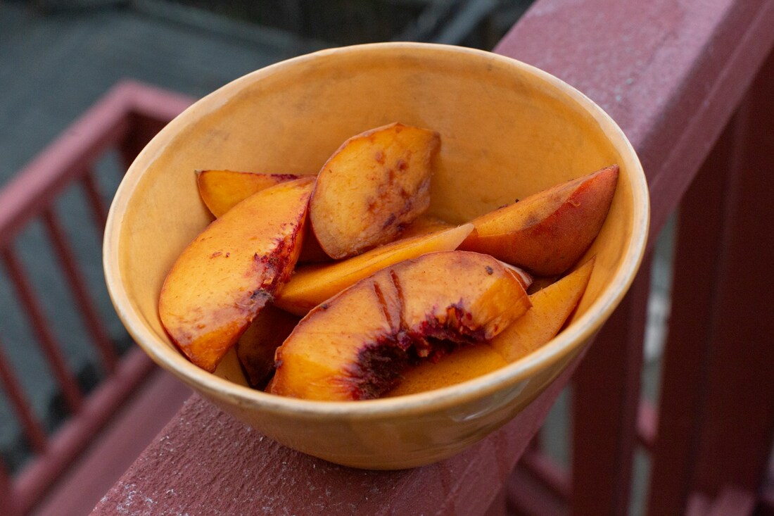 An ivory coloured bowl contains sliced peaches and sits on the edge of a red stair railingPicture