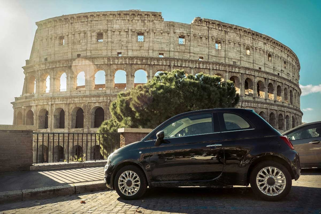 A small black car is parked in front of the Colosseum Picture
