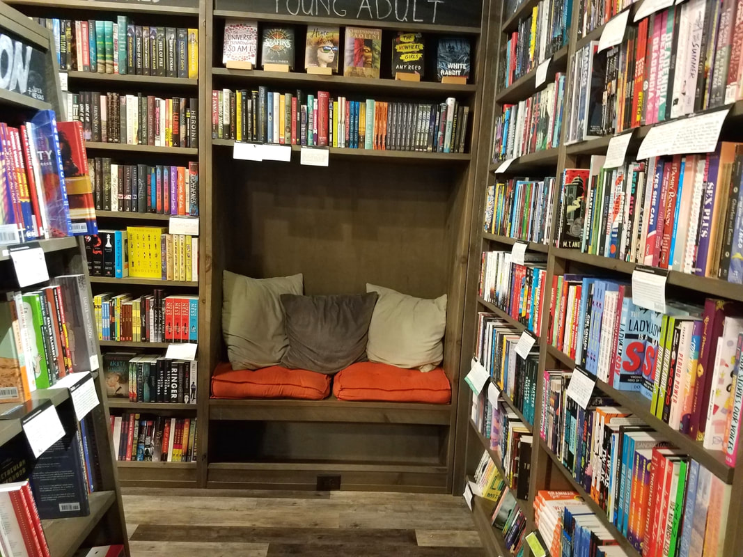 This is a bookstore & Bookbug: A padded reading nook with cushions set among the bookshelvesPicture