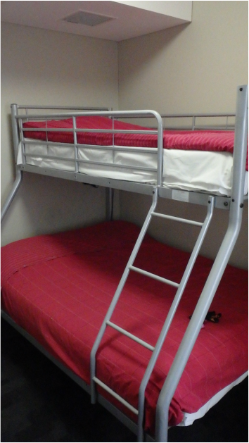 A hostel bunk bed with red blankets
