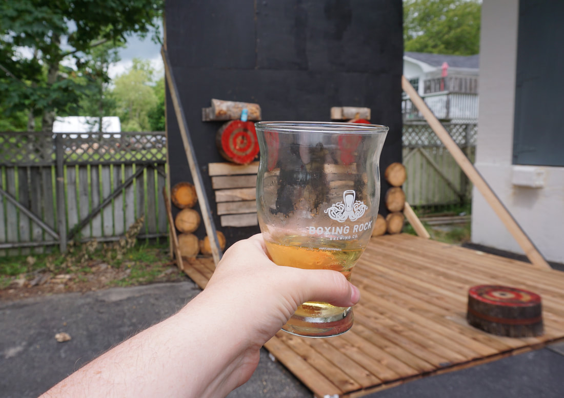 A glass of Boxing Rock beer in the foreground, axe throwing target in the background.