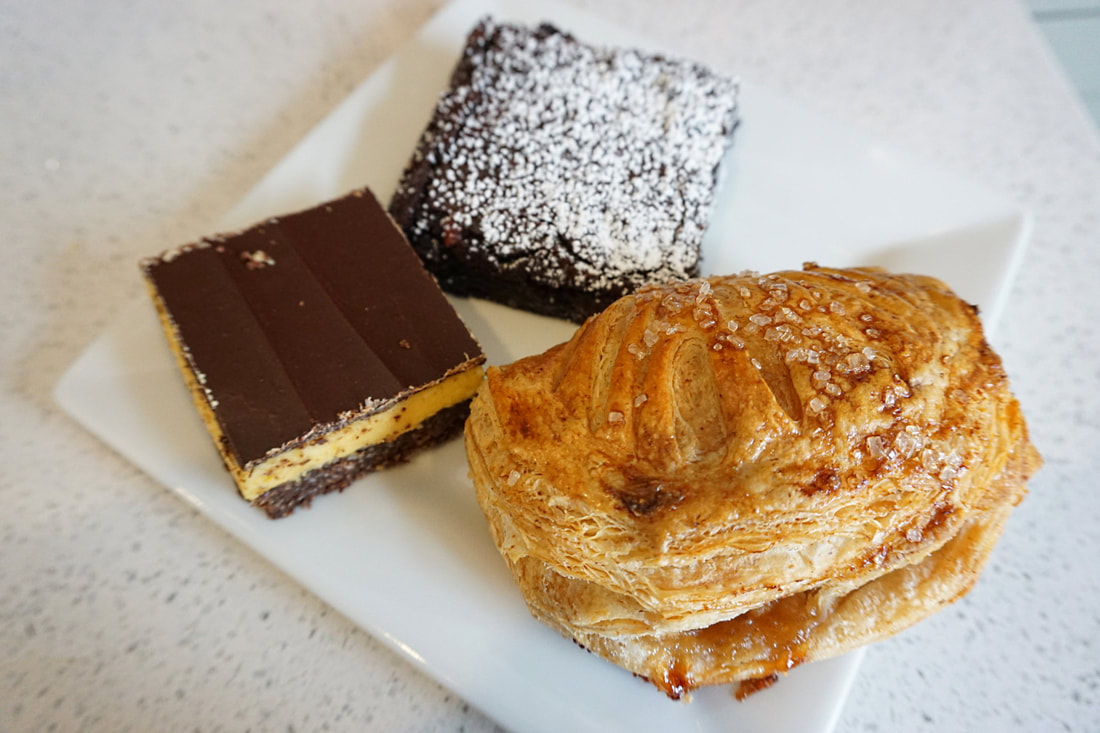 An apple turnover, a brownie, and a nanaimo bar site on a white plate Picture