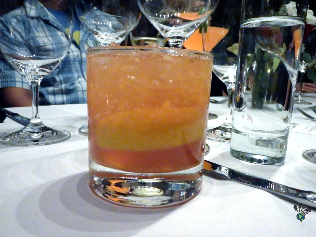 Brown-orange cocktail with lots of ice and a lemon wedge inside at Plonk Missoula Picture