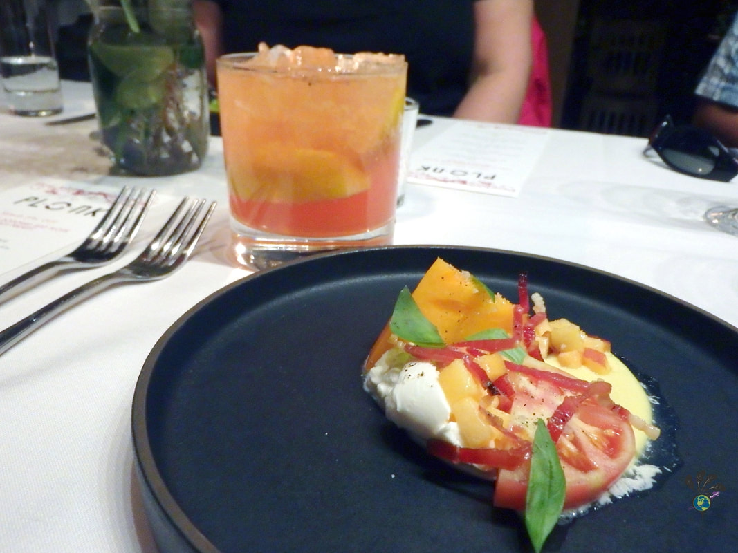 Black plate with a tomato salad with basil and peaches and cheese at Plonk Missoula Picture