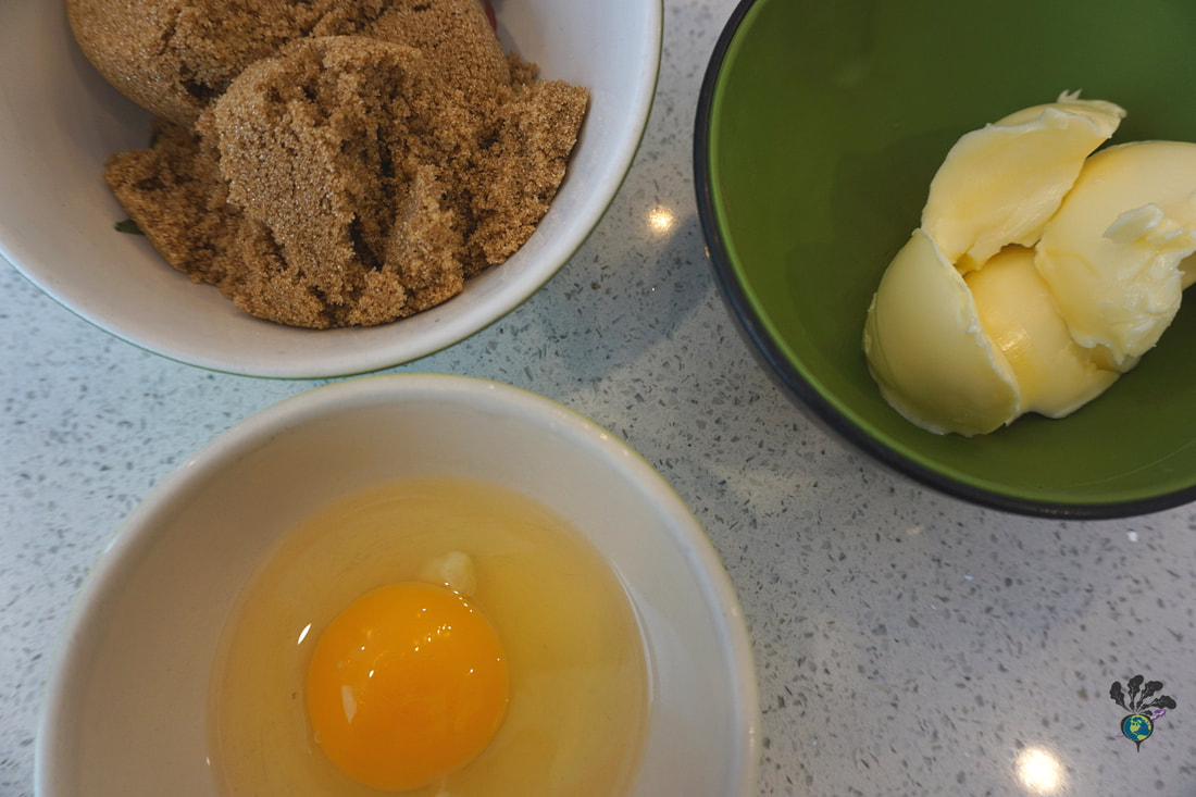 Three little bowls containing butter, brown sugar, and an egg.Picture
