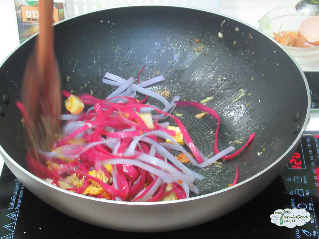 Rainbow colored pad Thai noodles cooking in the wok at our Bangkok cooking class 