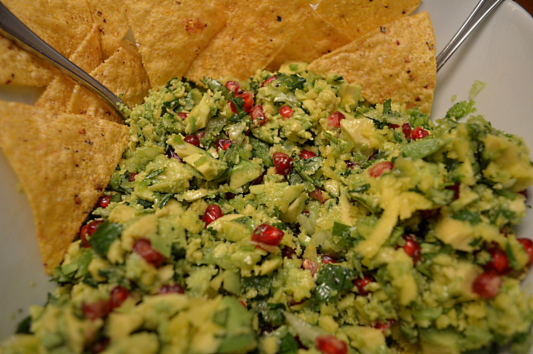 Avocado mango salad with red pomegranate seeds and tortilla chips in a bowl 