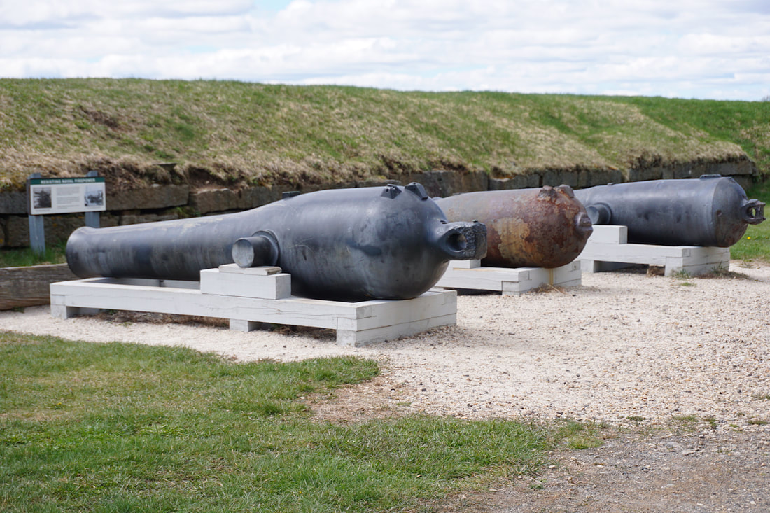 Three large cannons sit next to an earthen wall defence system