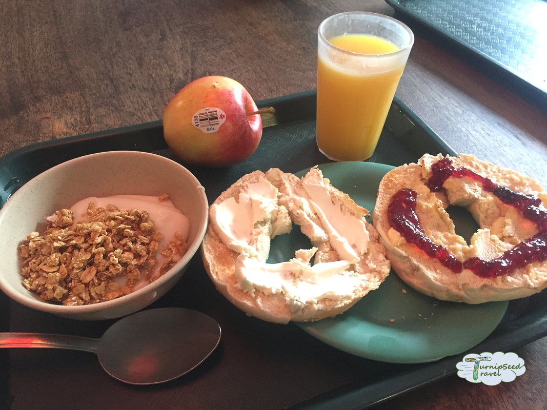 Free breakfast at HI Washington DC, including orange juice, apple, yogurt with granola, and a bagel with cream cheese and jelly. Picture