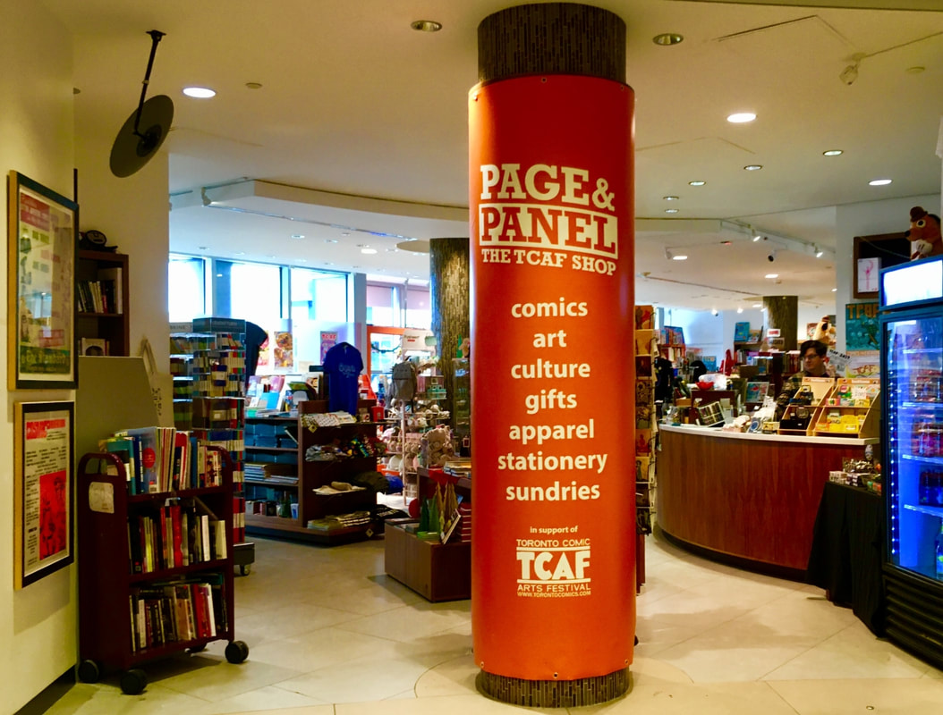 Interior of Page and Panel, with a large round pillar wrapped in orange advertising the store's services in the middle Picture