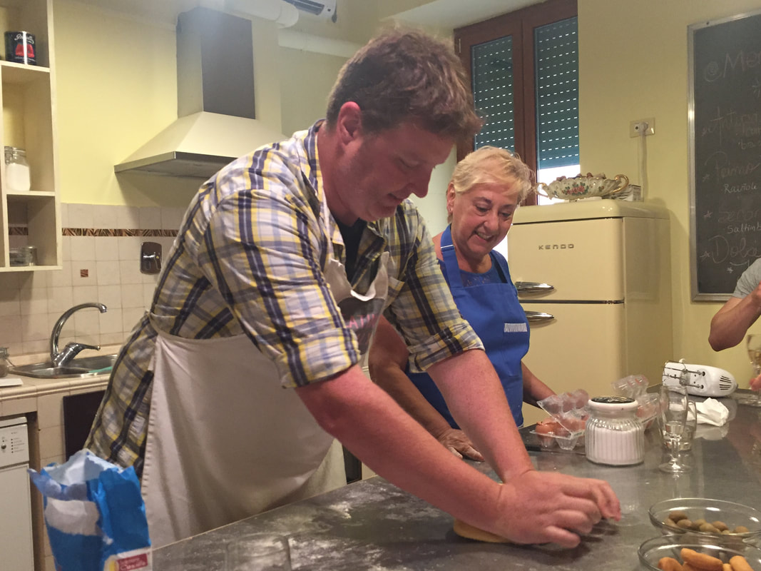 Ryan and a grandmother in Rome roll out pasta dough on a stainless steel table.