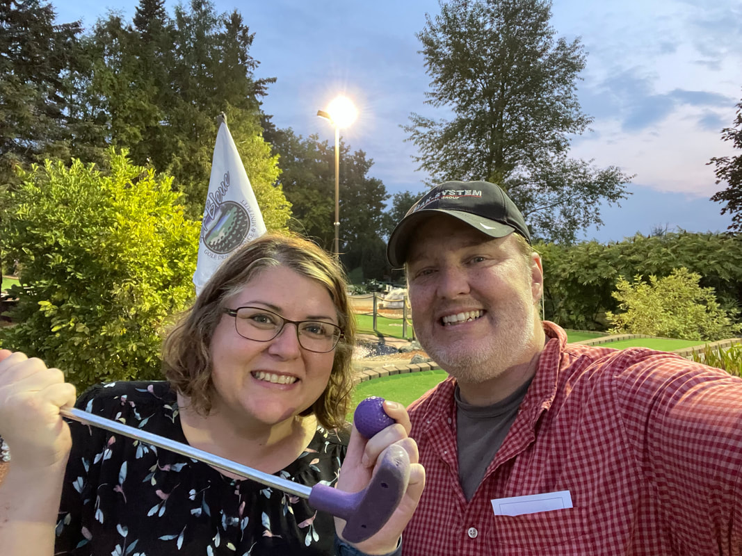 Ryan and Vanessa take a selfie on the mini golf course and pose with a purple ball and putter Picture