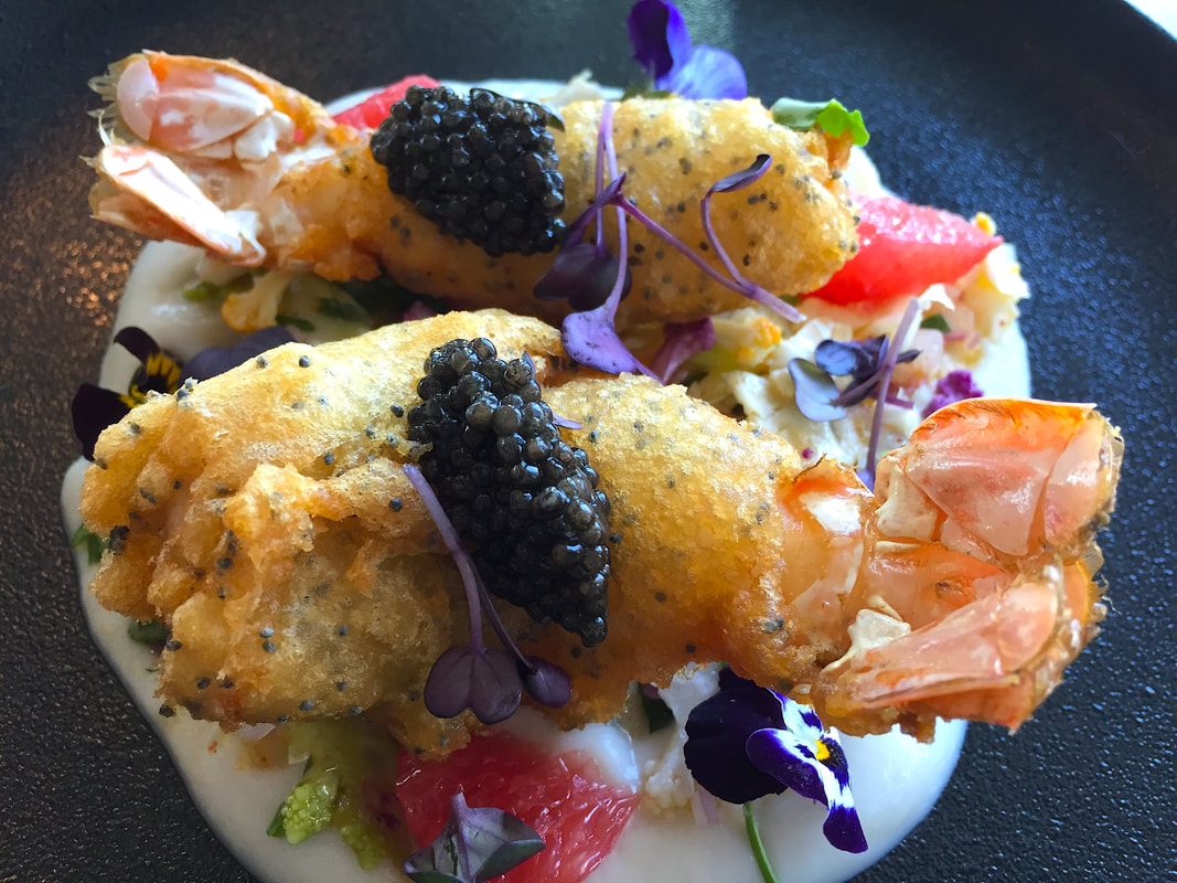 Deep fried tempura langoustines with black caviar and edible flowers and grapefruit