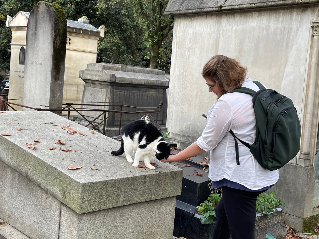 Vanessa pats a black and white cat in a cemetary.