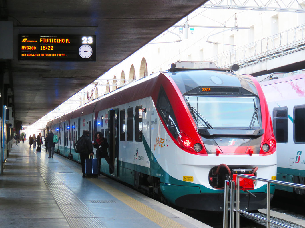 A green, red, and white train awaits departure at the train station.Picture