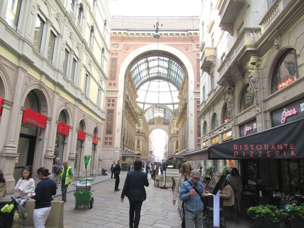 Walking through Galleria Vitorrio Emanuele among buildings with rounded arches and high windows Picture