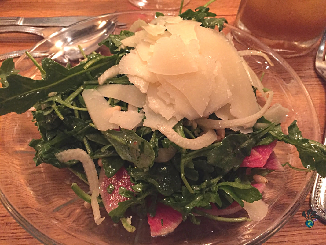 Arugula salad on a glass plate with pecorino cheese on top at Tupelo Grille WhitefishPicture