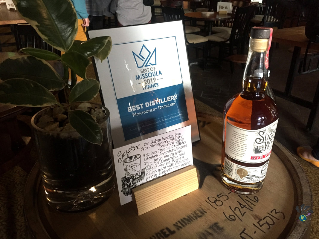 Bottle of whiskey and an award plaque sit on top of a whiskey barrel at Montgomery Distillery in Missoula MontanaPicture