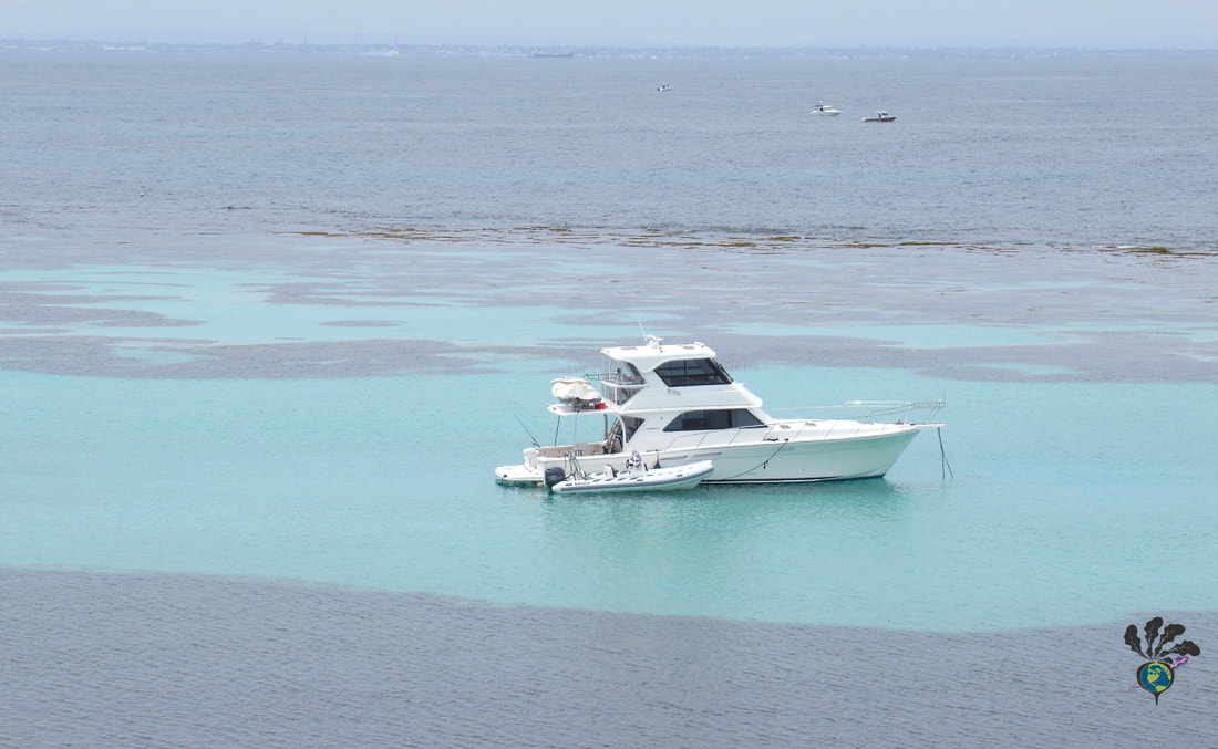 Small private yacht sits in light blue waters 
