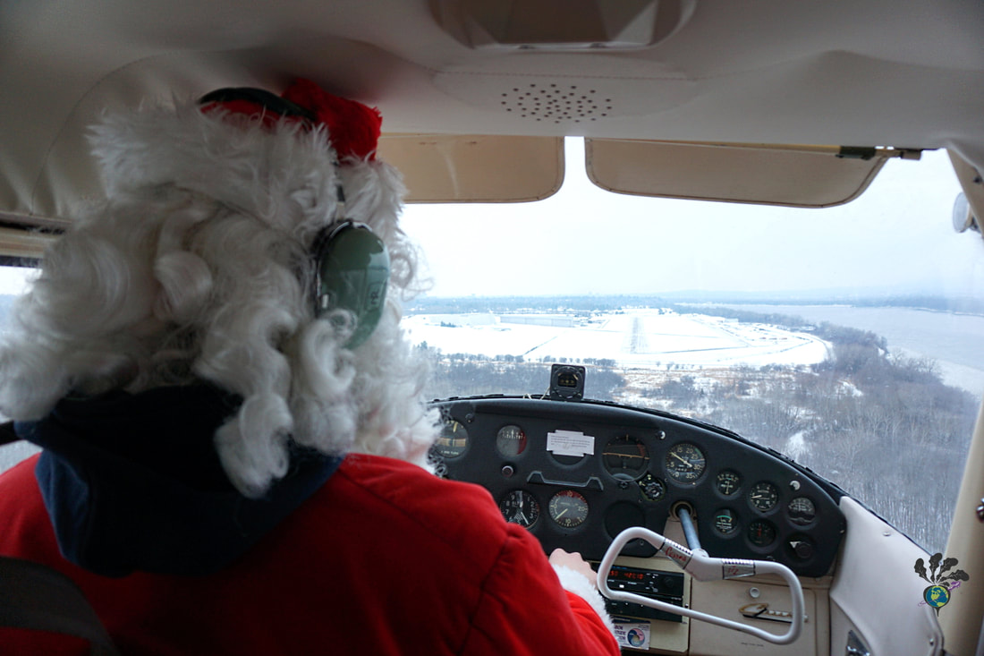 Santa flies the plane and looks at the snow-covered run way in front of him.