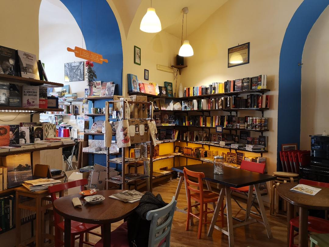 Bookstore interior with white walls and blue arches, small tables, and bookshelves 