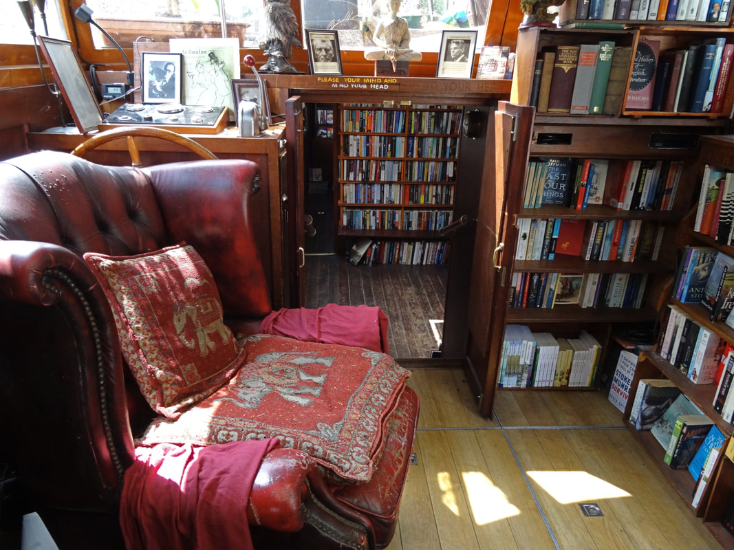 Interior of Word On The Water - a red leather arm chair in a corner surrounded by book shelves Picture