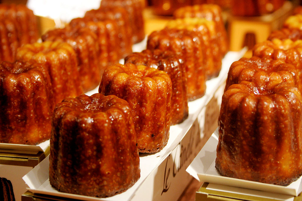 Rows of brown glistening caneles on a tray
