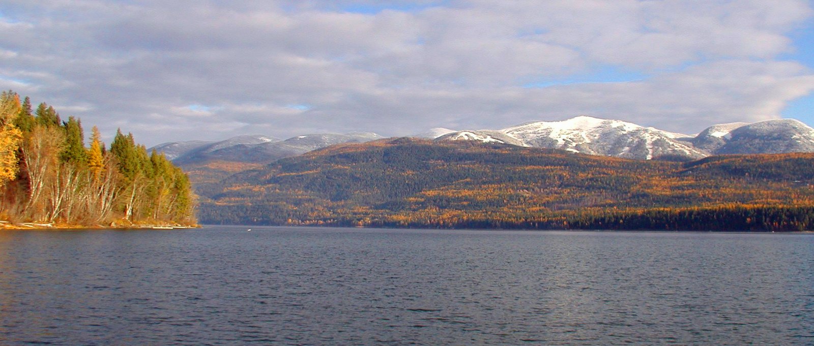 A large deep blue lake with hills and mountains in the backgroundPicture