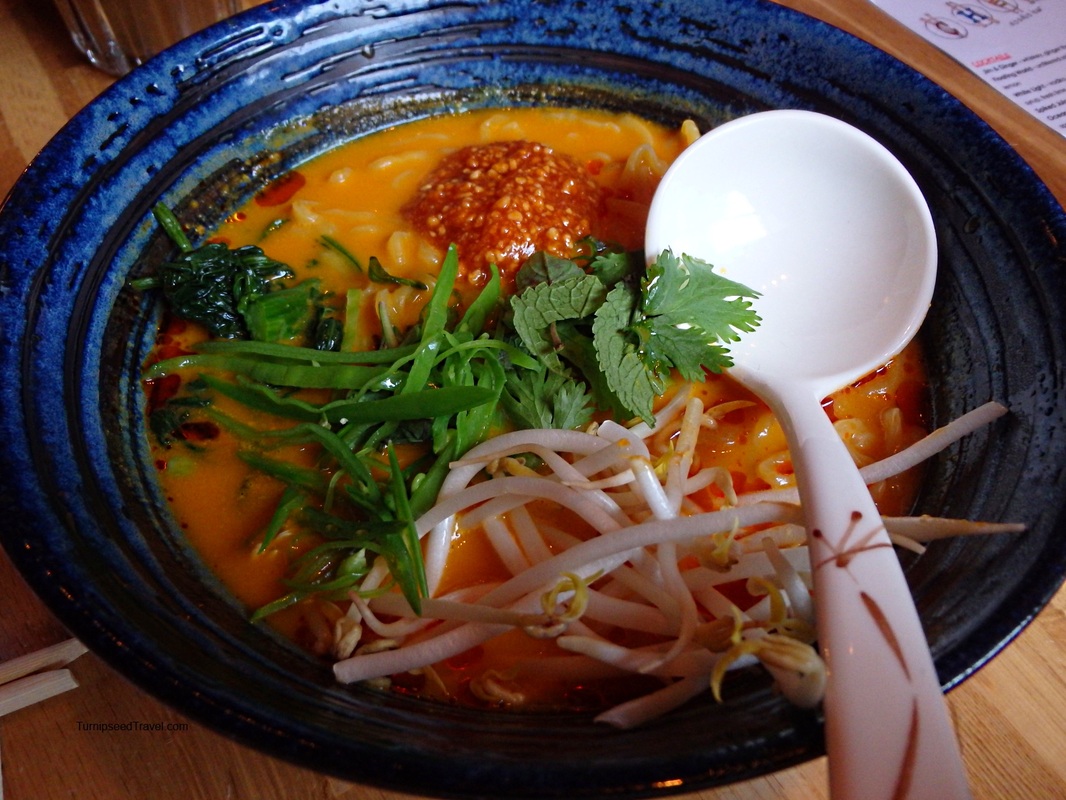 A colorful bowl of noodle soup topped with herbs and spicesPicture