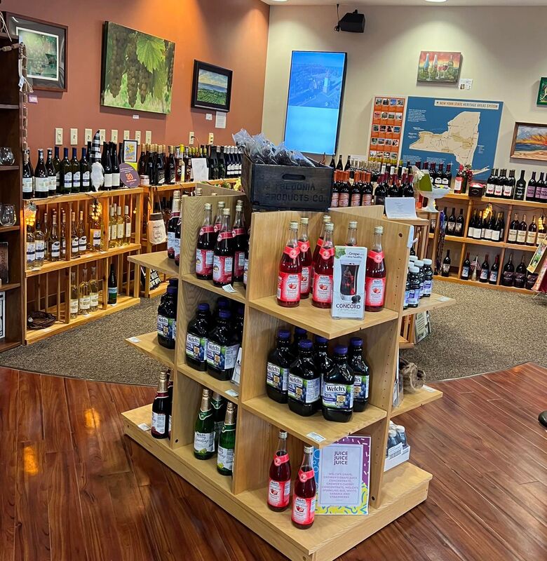 A brightly lit showroom with multiple shelves and displays of wine and grape juice in glass bottlesPicture