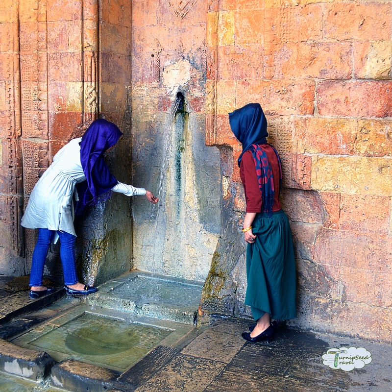 Urfa Mardin Turkey: Two young women in bright blue headscarfs stand at a water pump