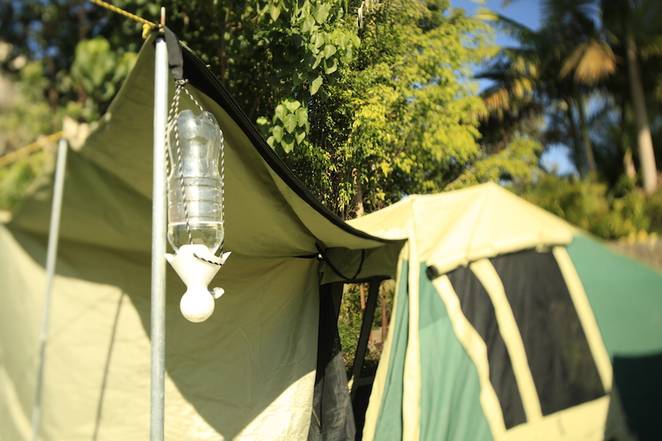 Set up showing a tent and a basic shower made from a water bottle.Picture