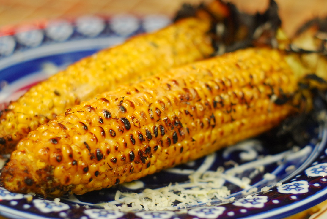 Two ears of roasted corn on a blue patterened plate