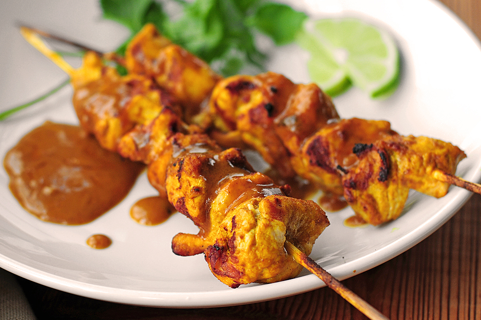 Two chicken kebabs covered with peanut sauce.
