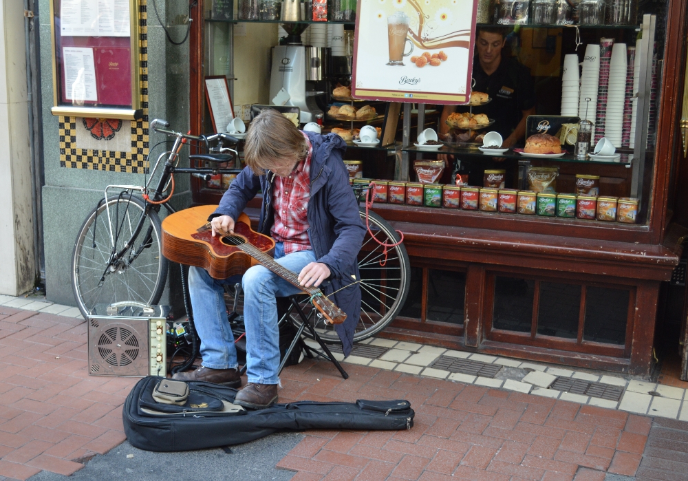 Man tunes a guitar outside a cafe in central Dublin Picture