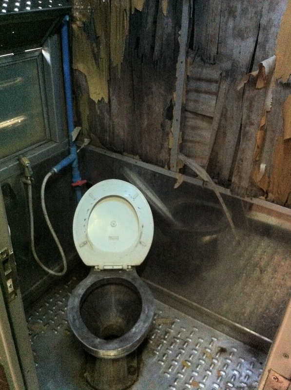 A toilet sits in a rundown train room