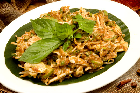A plate of spicy noodles sitting on a green banana leaf