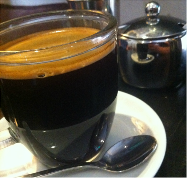 Close up of a glass mug with black coffee and a thick crema 