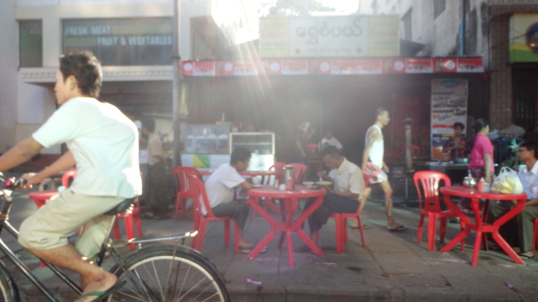 Colorful sidewalk cafe in Yangon with red chairs