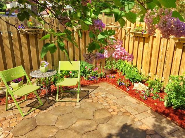 Stone patio in a backyard with chairs and flowers