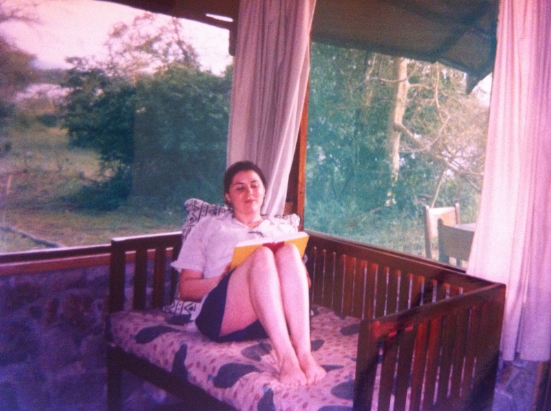 Young Vanessa sits on a daybed, reading a book