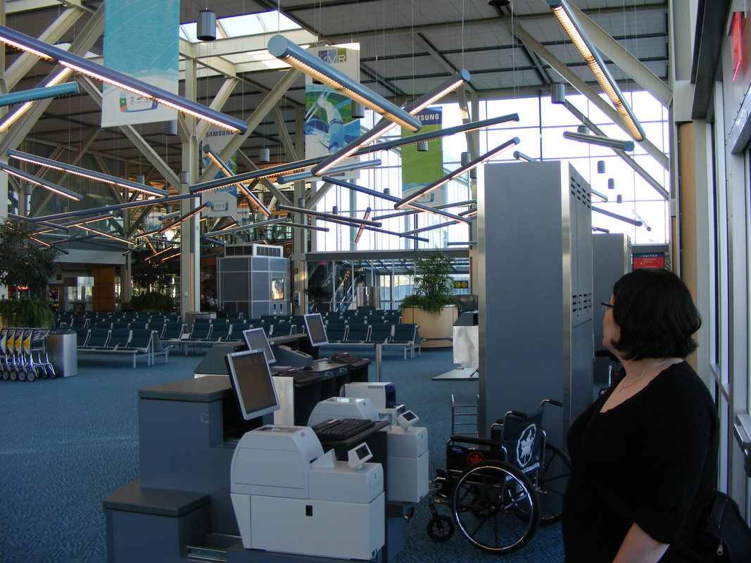 Vanessa wears a black shirt and looks at the terminal in Vancouver Airport