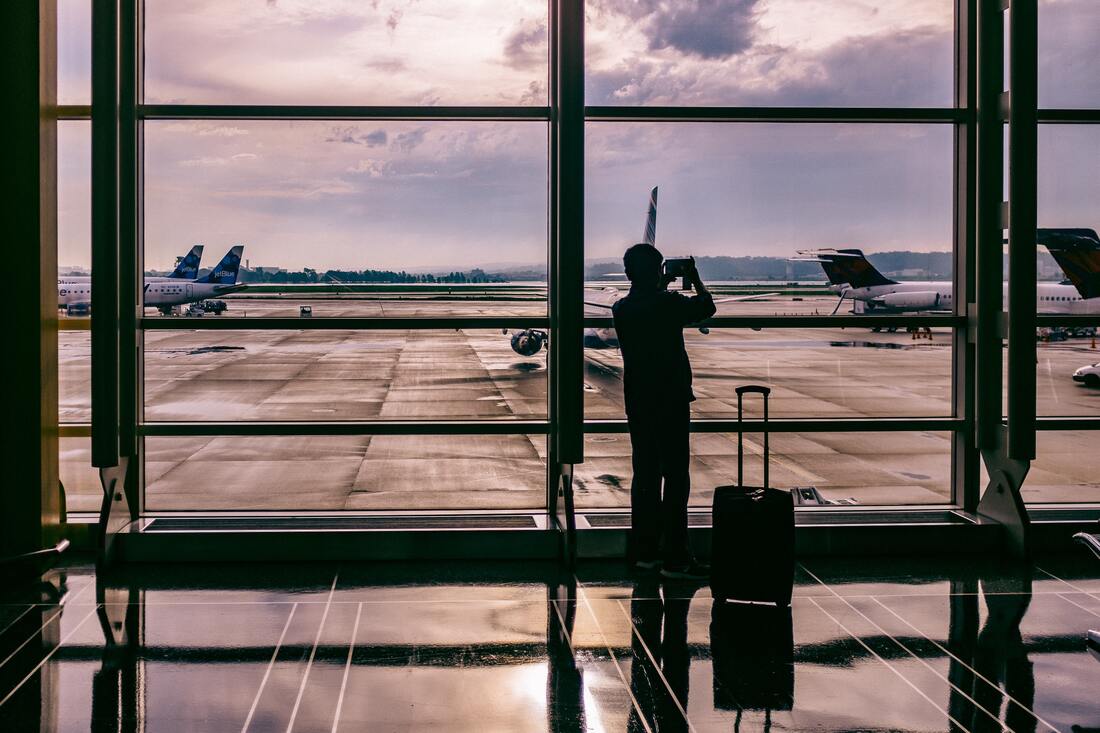 Canadian Transportation Agency Flight Delay Compensation Rules. Passenger looks out a huge glass window at planes waiting to take off