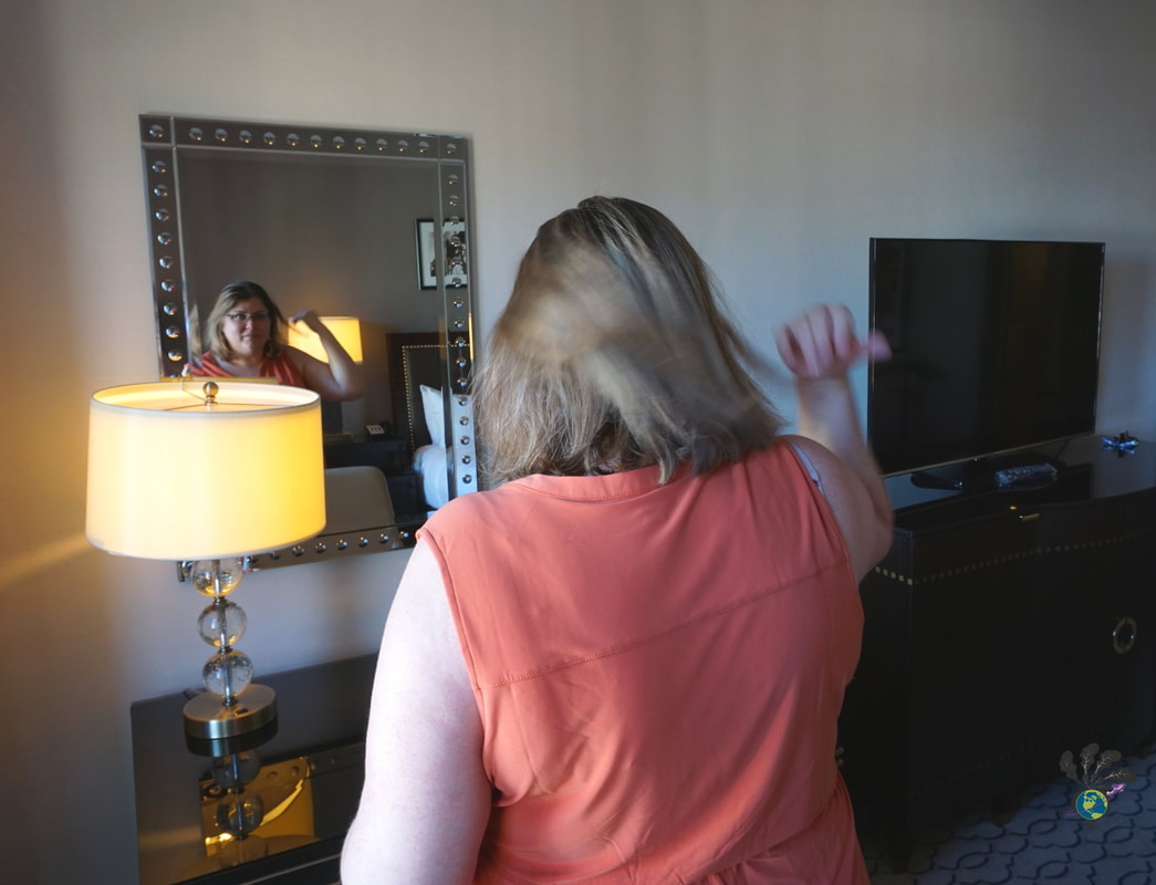 Vanessa looks in the mirror at Chateau Laurier while wearing an orange dress