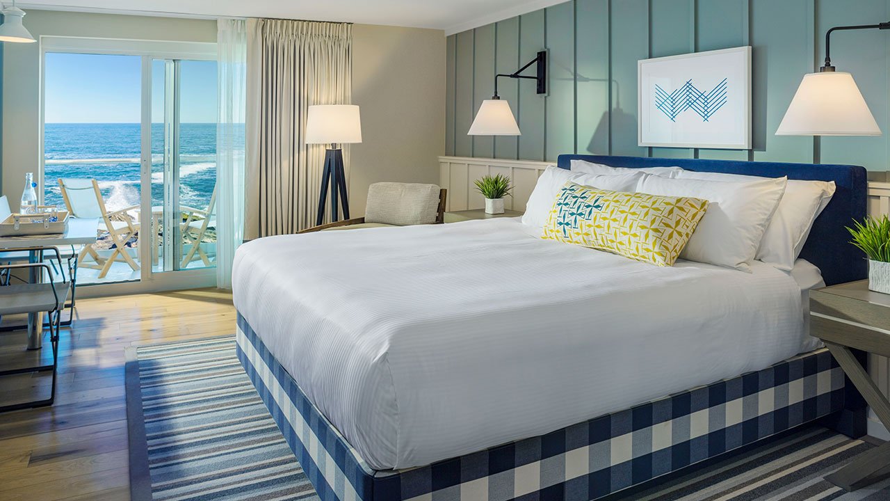Blue and white bedroom with a window showing a view of the ocean in the background Picture