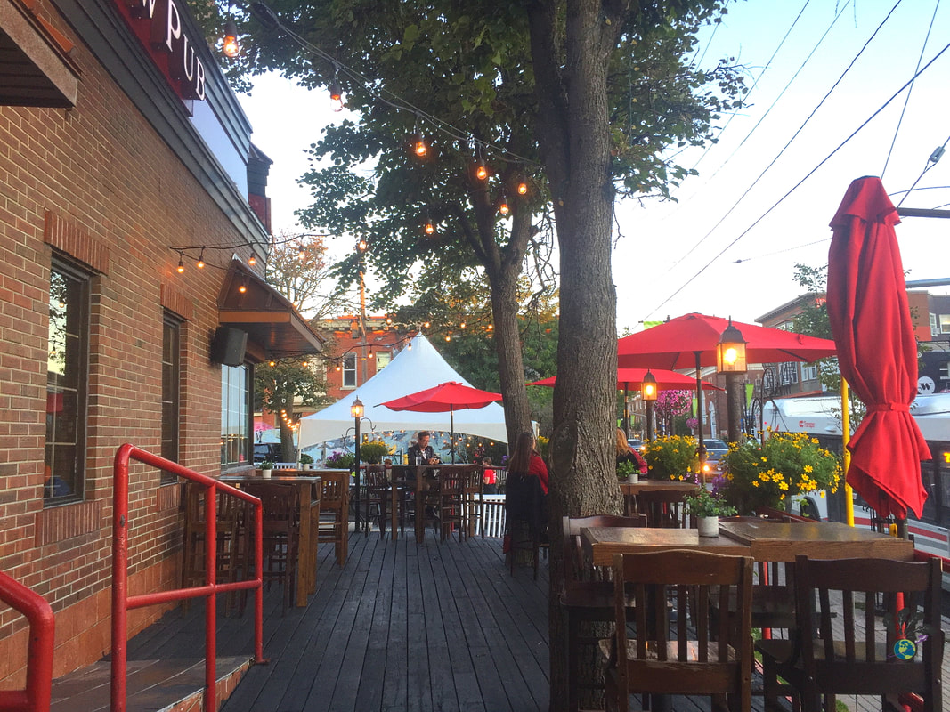 Outdoor patio of the Clocktower Brew Pub, featuring a brick building, red umbrella, and festive twinkle lights