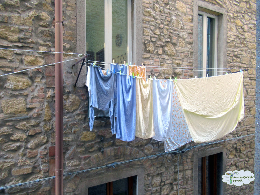Colorful clotheslines along cobblestone streets in Volterra, one of the best Tuscan villages. 
