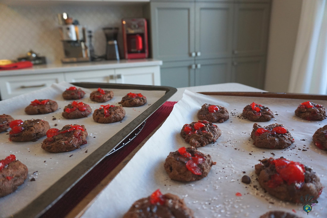 Trays of cookie sheets covered in parchment paper with freshly baked Black Forest cookies and kitchen pantry cupboards are visible in the backgroundPicture
