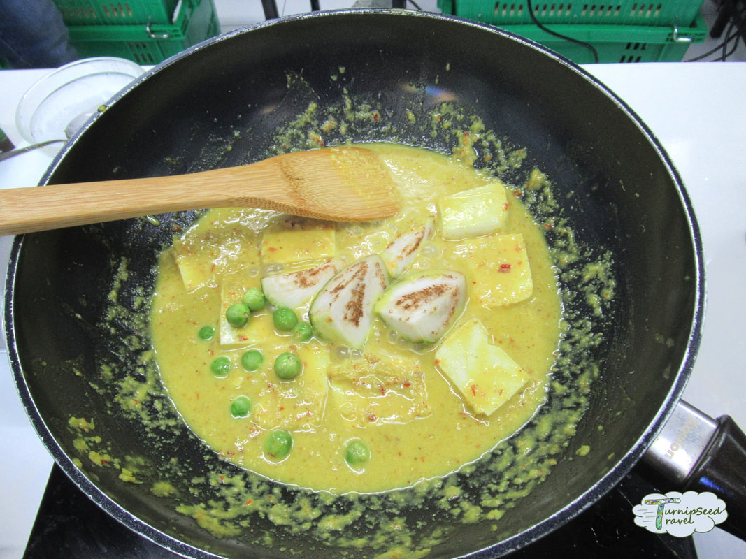 A wok of chicken curry cooking with coconut milk at a Bangkok cooking class 