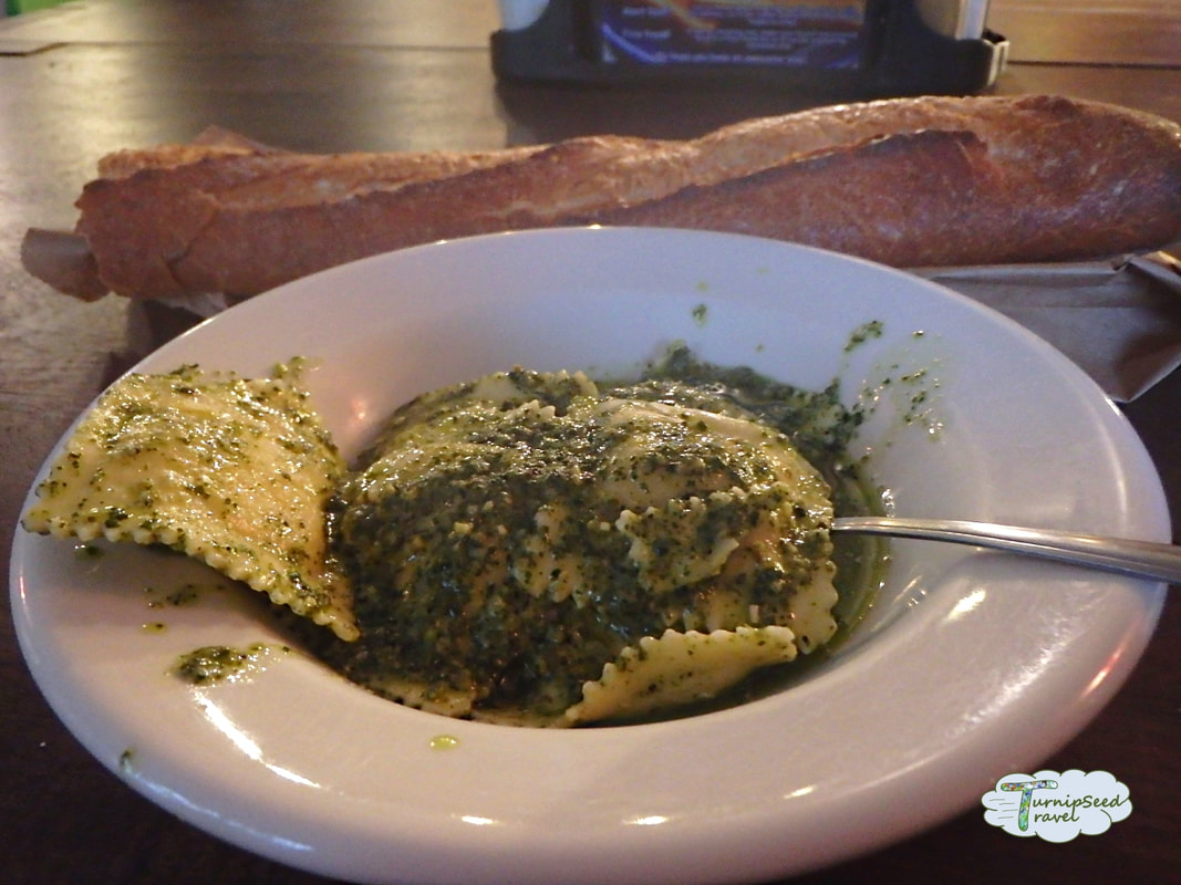 Bowl of pesto covered ravioli with a baguette in the background Picture